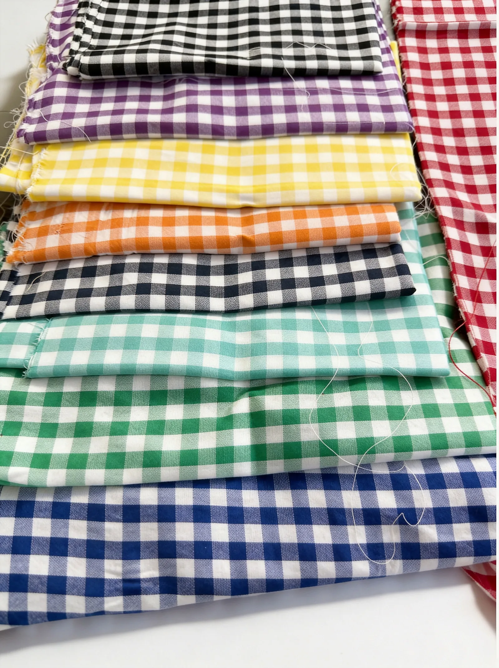 Item 7702 cotton vichy gingham fabric folded stack showing multiple colorways